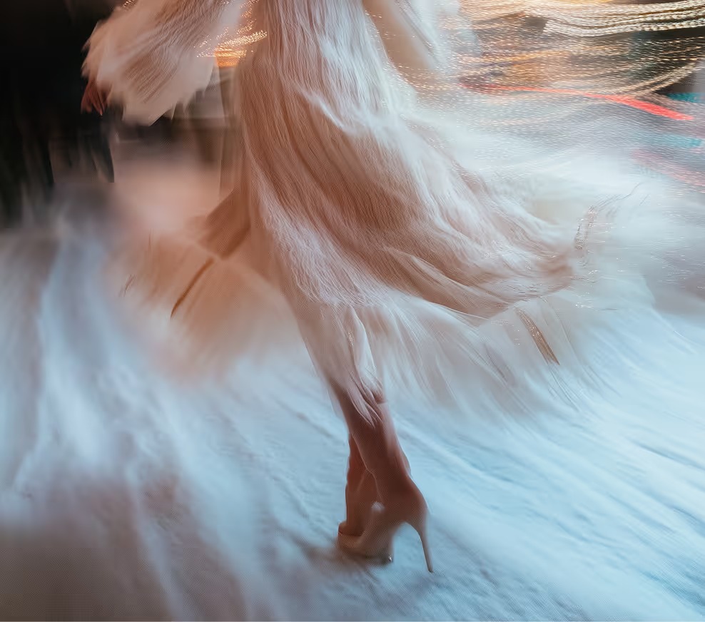 Vestido de novia en movimiento durante el baile, con luces de fiesta de fondo