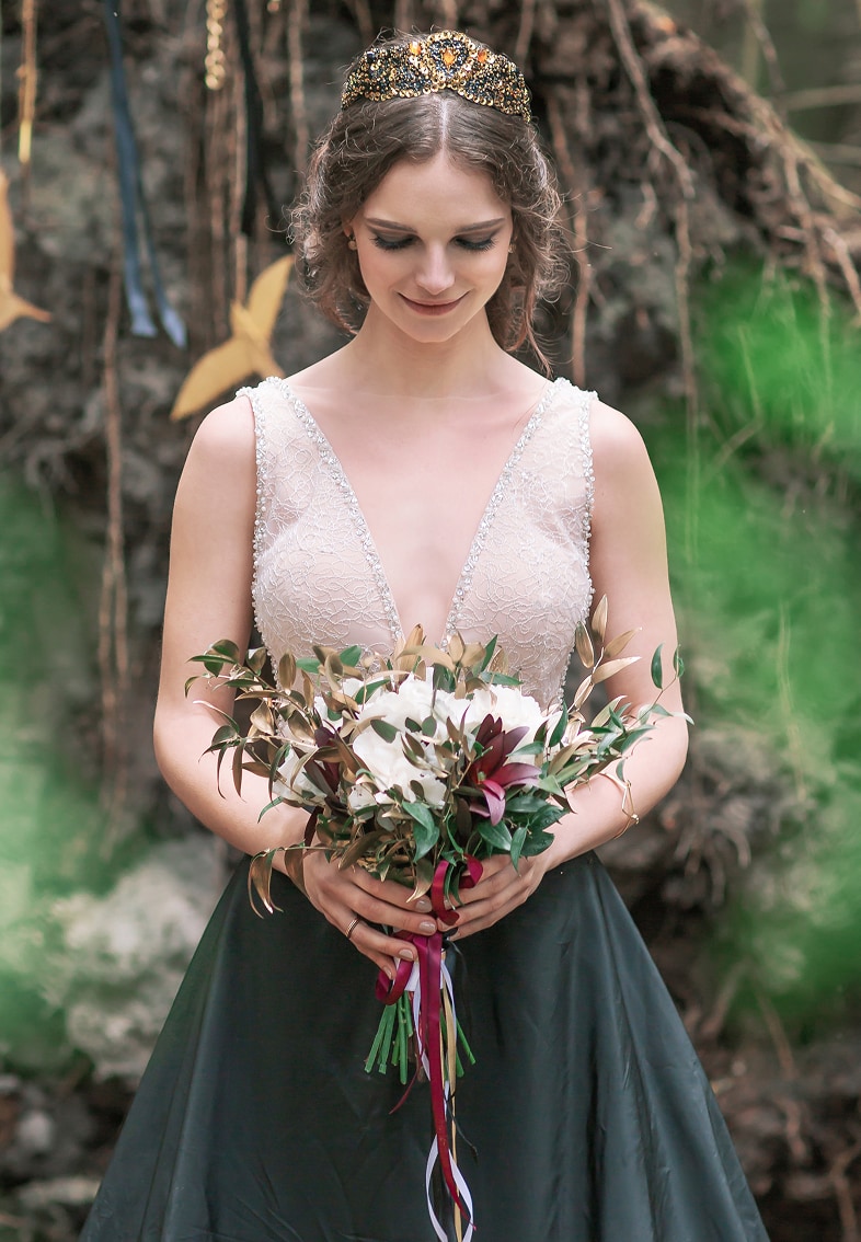 Los novios sosteniendo un ramo de flores silvestres con margaritas y capullos azules y blancos.